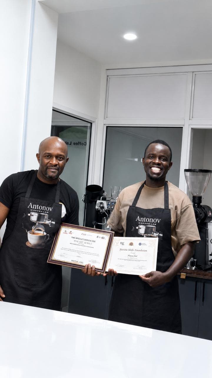 Two Antonov graduates holding their barista and coffee-grading certificates at the coffee lab